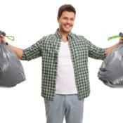 A man holding two bags of trash.