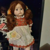 Value of a Victoria Ashlea Porcelain Doll - doll wearing a red print dress with an eyelet apron