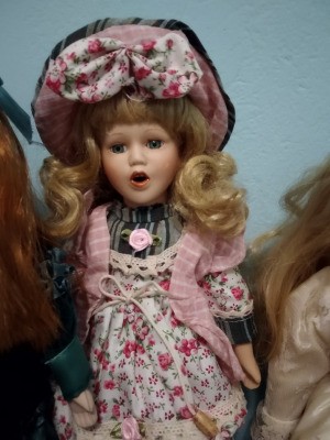 Identifying a Porcelain Doll - doll wearing plaid dress with floral jumper and matching hat