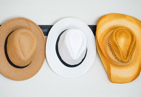 A collection of hats hanging on a wall coat rack.