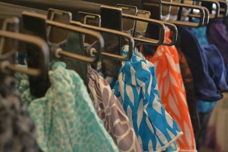 Clothing clipped on hangers in a closet.