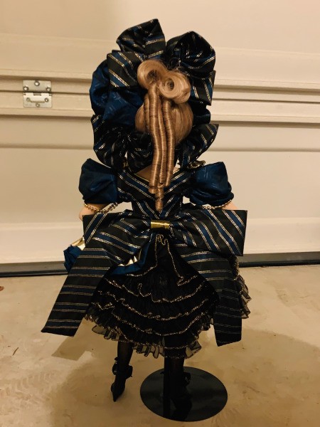 The back of a porcelain doll wearing a black outfit.