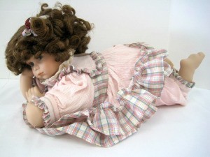 Identifying a Porcelain Doll - doll in pink and plaid outfit lying down