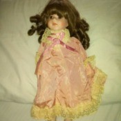 Value of a Brinn Porcelain Doll - dark haired doll wearing a pink lace trimmed outfit
