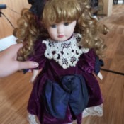 Identifying Porcelain Dolls - doll with ringlets wearing a plum colored dress with white lace trim