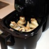 An air fryer with chicken wings inside.