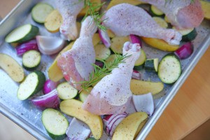 Chicken and vegetables being cooked on a sheet pan.