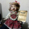 Value of a Seymour Mann Porcelain Doll - doll wearing a red plaid dress holding a certificate