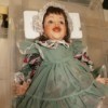 Identifying a Porcelain Doll - doll wearing a patchwork pattern dress with a green pinafore over it