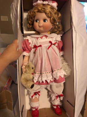 Identifying a Porcelain Doll - doll wearing a red gingham dress with a white pinafore