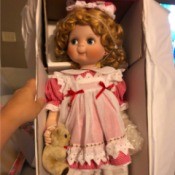 Identifying a Porcelain Doll - doll wearing a red gingham dress with a white pinafore