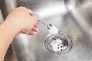 A sink drain being deodorized with baking soda.