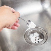 A sink drain being deodorized with baking soda.