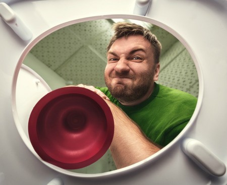 A man using a toilet plunger.