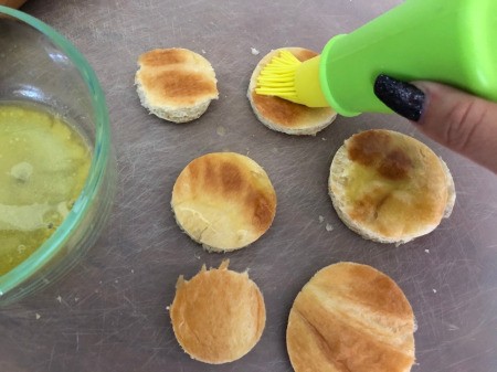 buttering rounds of croissants