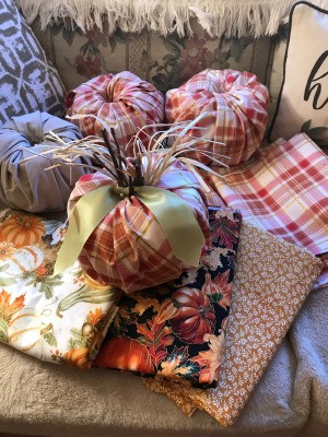 Crafty Toilet Paper Roll Pumpkins  - finished pumpkin sitting on a stack of fabric and three more without stems in background