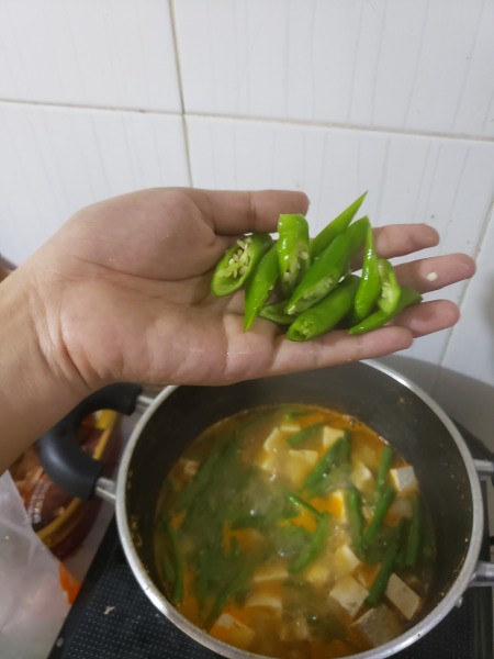 adding peppers to soup