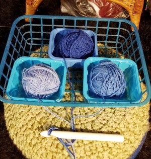 Three balls of yarn that are in different containers to avoid tangling.