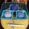 Three balls of yarn that are in different containers to avoid tangling.