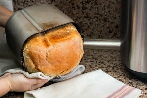A loaf of bread coming out of a bread machine.