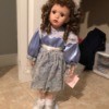 Value of a Paradise Porcelain Doll - doll in stand, wearing a blue satin dress with lace trim