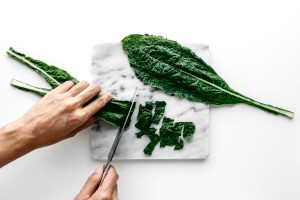 Kale leaves being chopped on a cutting board.