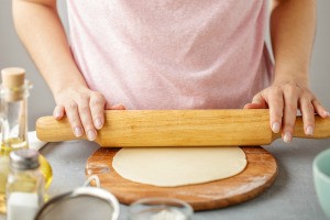 A corn tortilla being rolled out to make chips.