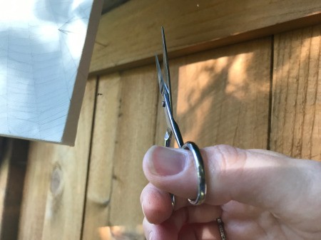 Catching a Spider Web - one person holds the canvas while the other carefully cuts the anchor threads and wraps them around the sides of the canvas