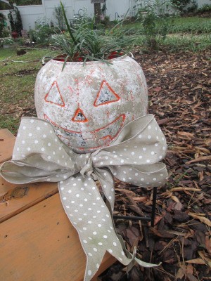 Stone Looking Pumpkin Planters - orange pumpkin outside with bow round the base and plant inside