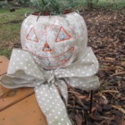 Stone Looking Pumpkin Planters - orange pumpkin outside with bow round the base and plant inside