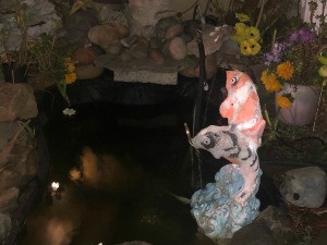 A fountain sculpture with two koi jumping.