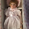 Value of Porcelain Dolls -doll wearing floral dress with matching hat and white eyelet lace apron