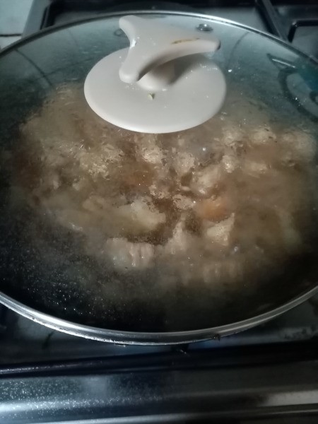 covered pan simmering with pork and water