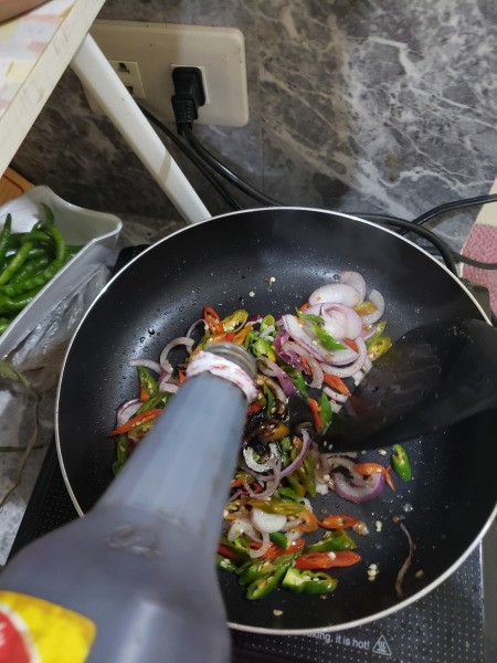 adding soy sauce to peppers & onions