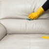 Someone wearing rubber gloves cleaning a leather couch.