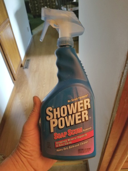 Buying Shower Power Cleaner - hand holding a bottle of Shower Power Cleaner