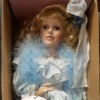 Value of a J. Misa Porcelain Doll - doll in a box wearing a pale blue dress and a feather boa.