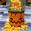 Crocheted Pumpkin Candy Jar Cover - pumpkin candy jar filled with candy corn, with some scattered around the jar on the table