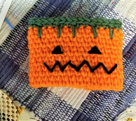 Crocheted Pumpkin Candy Jar Cover - eyes, mouth and green at top