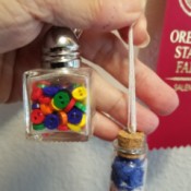 Two tiny hanging glass jars filled with beads or buttons.