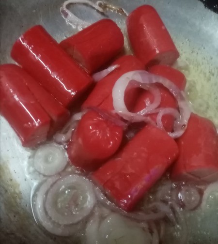 adding hotdogs to onions