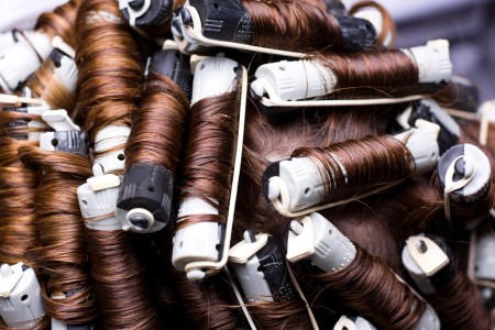 Curlers in brunette hair for a perm.