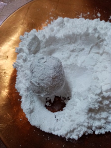 rolling ball of dough in powdered sugar