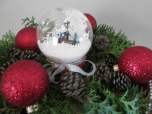 Budget Friendly Snow Globe - filled globe surrounded by red Christmas ornaments, pine cones, and greenery