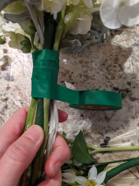 Adding Fresh Flowers to Cake Decoration - closeup of wrapping the tape around the stems