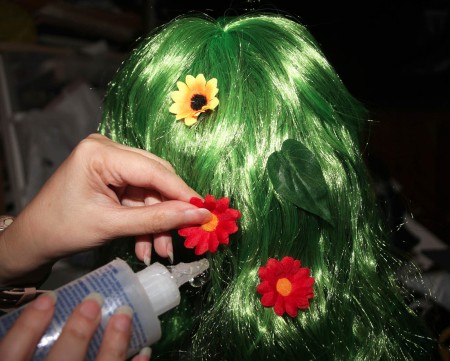 Attaching flowers to a green wig.
