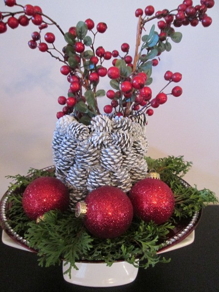 Pine Cone Vase - vase surrounded by greenery and red ornaments and filled with faux berry srays
