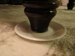 A saucer under a heavy table leg.