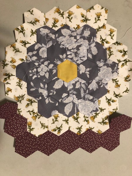 English Paper Pieced Flower Pillow - yellow round complete, adding the final round of the maroon hexagons
