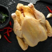 A whole chicken being prepared for cooking.